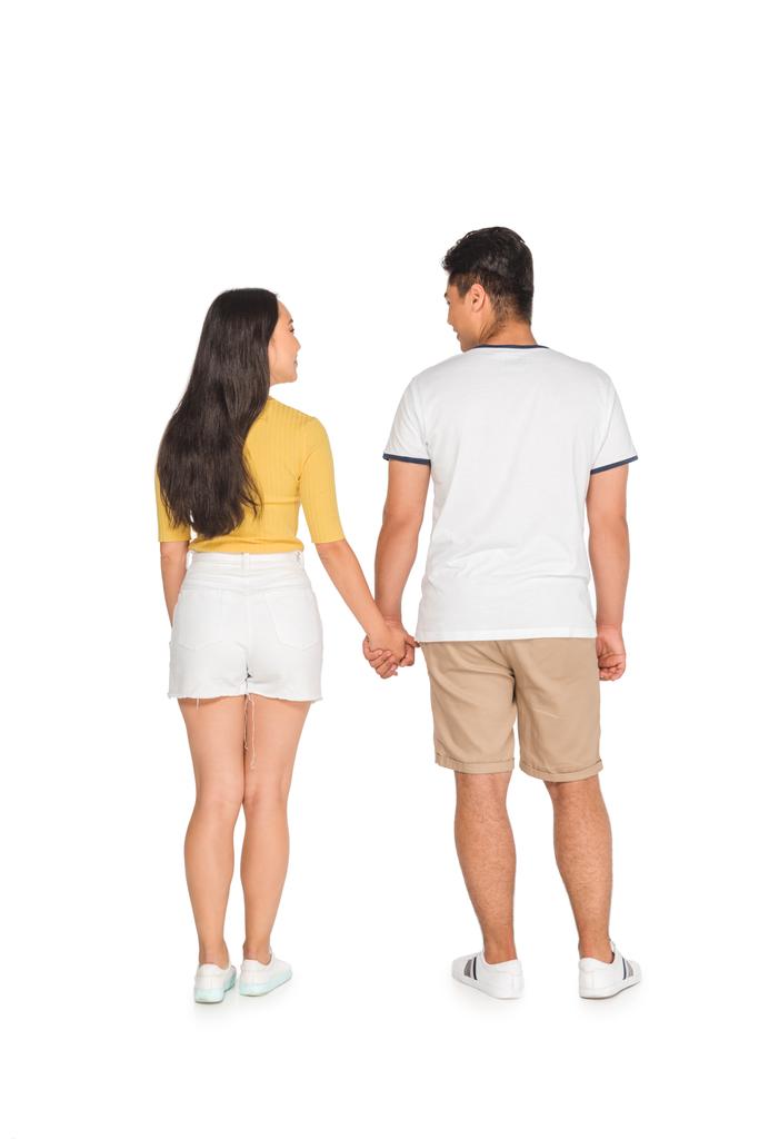 back view of young man and woman in summer clothing holding hands on white background - Photo, Image