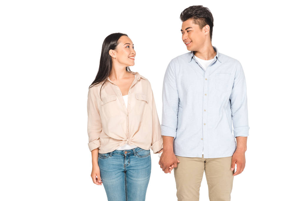 щаслива азіатська пара тримає руки і дивиться один на одного ізольовано на білому
 - Фото, зображення