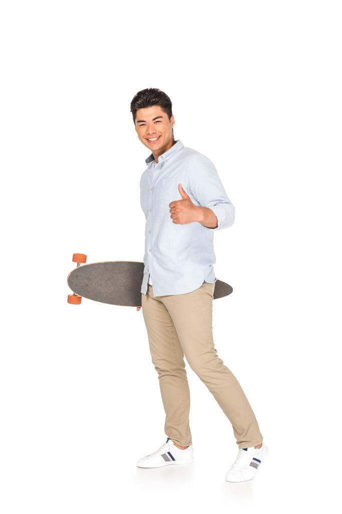 joven asiático hombre celebración longboard mientras mostrando pulgar arriba en blanco fondo
 - Foto, Imagen