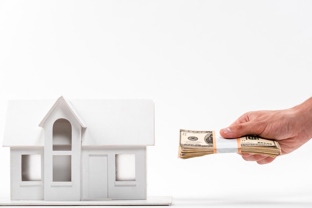 vista cortada do homem segurando notas de dólar perto da casa da caixa no branco
 - Foto, Imagem