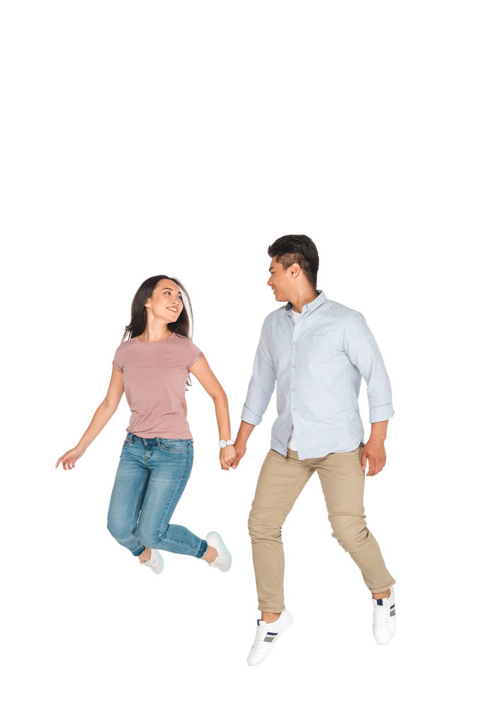 feliz asiático hombre y mujer saltar mientras cogido de la mano en blanco fondo
 - Foto, imagen