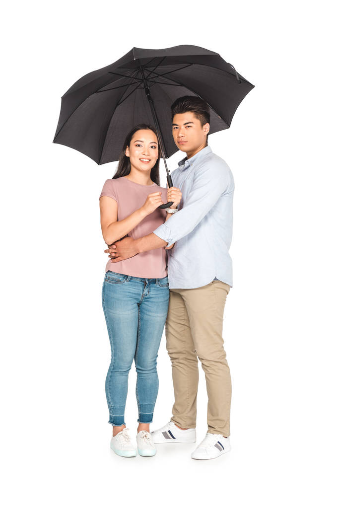 молодой азиат обнимает девушку, стоя под зонтиком вместе на белом фоне
 - Фото, изображение