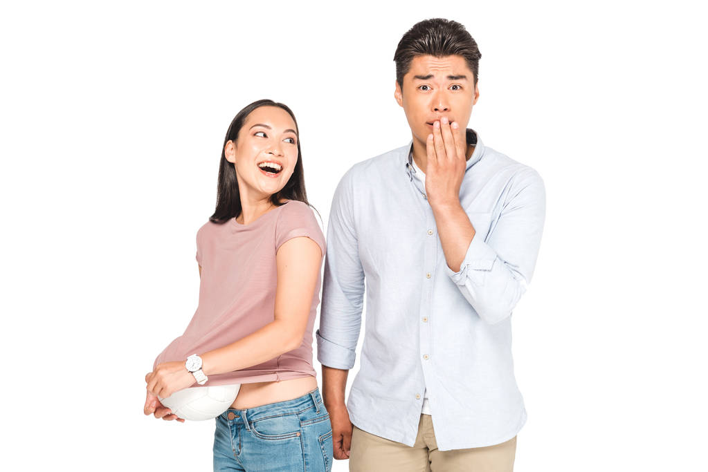 choqué asiatique homme regardant caméra tandis que copine obtention balle hors de t-shirt isolé sur blanc
 - Photo, image