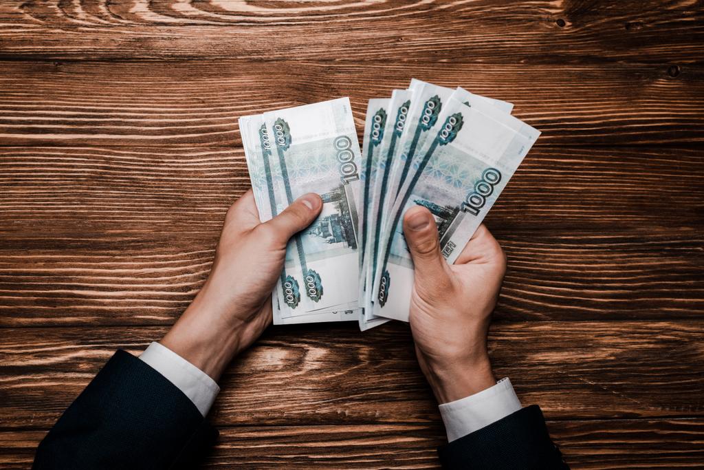 bovenaanzicht van de man tellen Russische geld in de buurt van tafel  - Foto, afbeelding