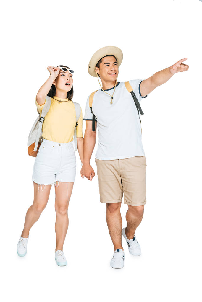 δύο νεαροί Ασιάτες τουρίστες που κρατούν τα χέρια και κοιτάζουν μακριά σε λευκό φόντο - Φωτογραφία, εικόνα