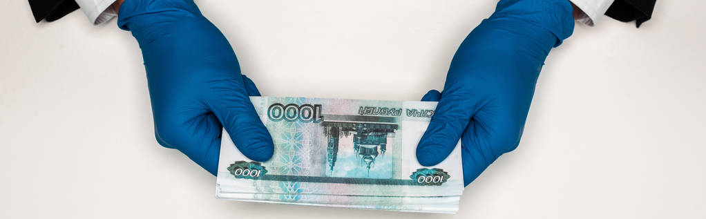 白にロシアのお金を保持する青いラテックス手袋の男のパノラマショット  - 写真・画像