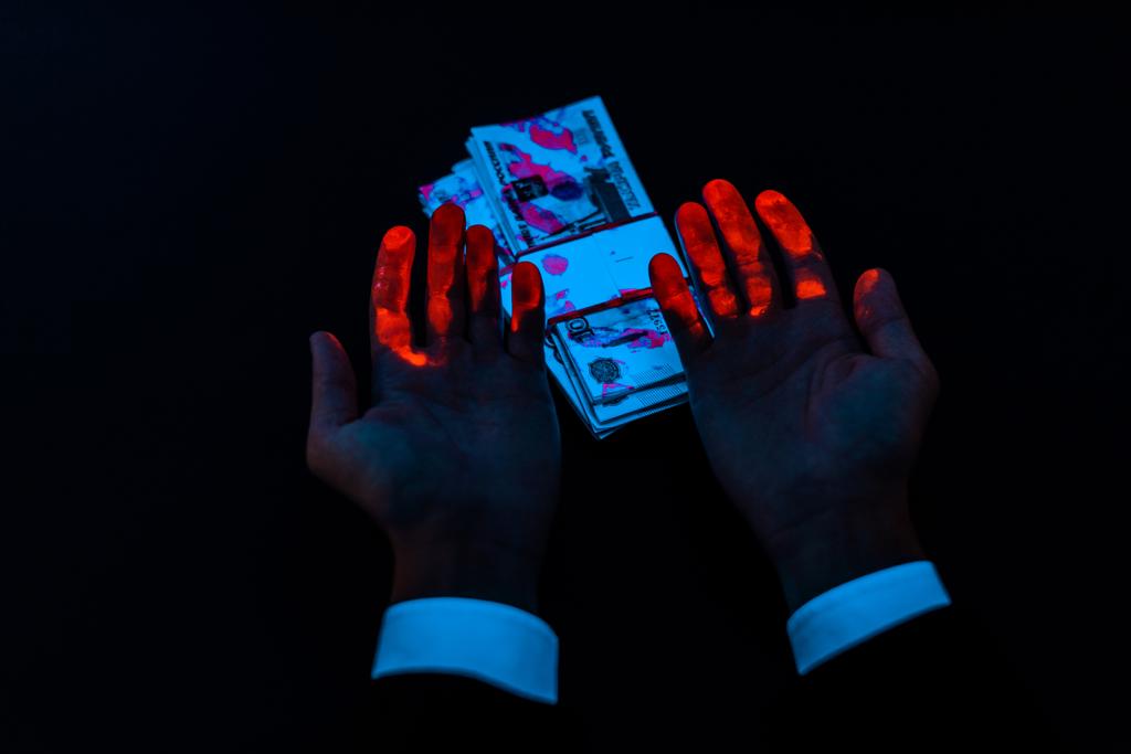 abgeschnittene Ansicht des Mannes in der Nähe russisches Geld unter UV-Beleuchtung isoliert auf schwarz  - Foto, Bild