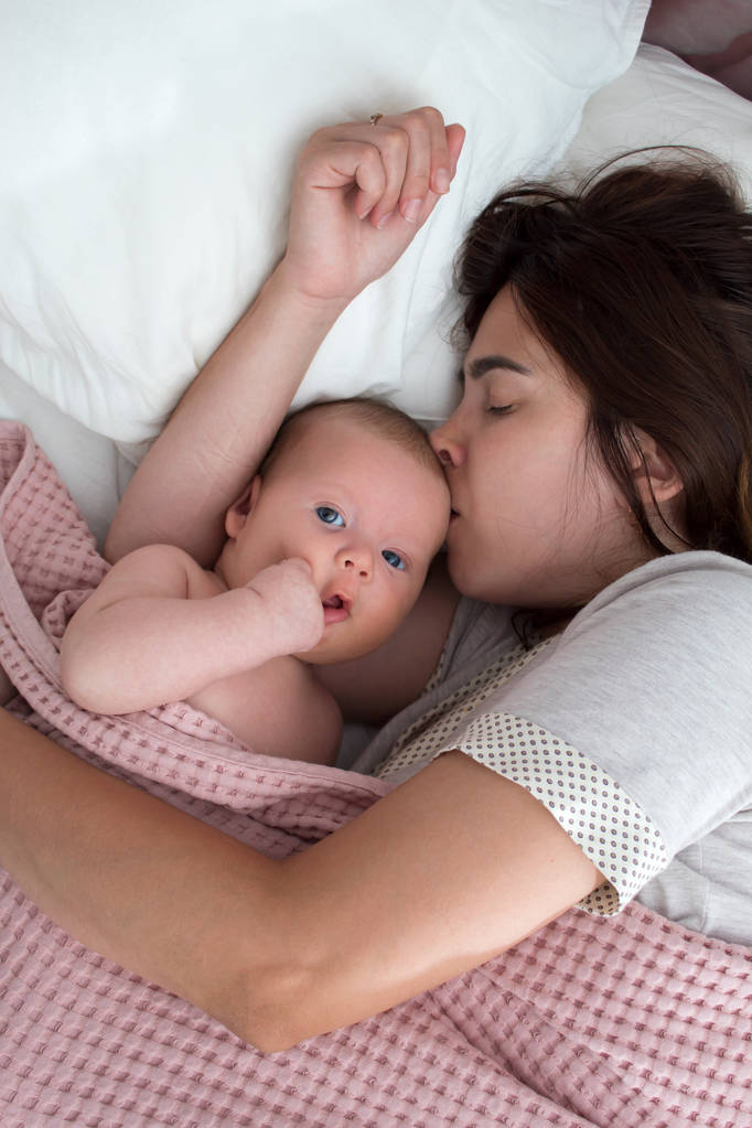 美しいブルネットの女の子は彼女の赤ちゃんにキス。寝室にいる - 写真・画像