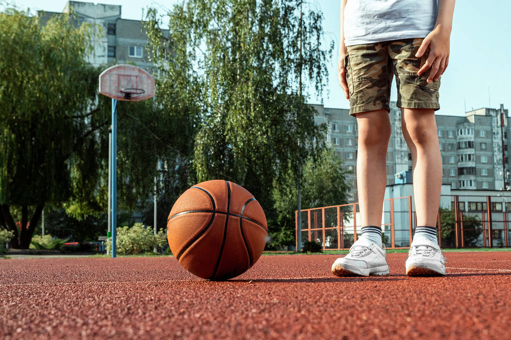 Basketbol sahasında basketbol topu olan bir çocuğun portresi. Bir spor yaşam tarzı kavramı, eğitim, spor, eğlence, tatil. - Fotoğraf, Görsel