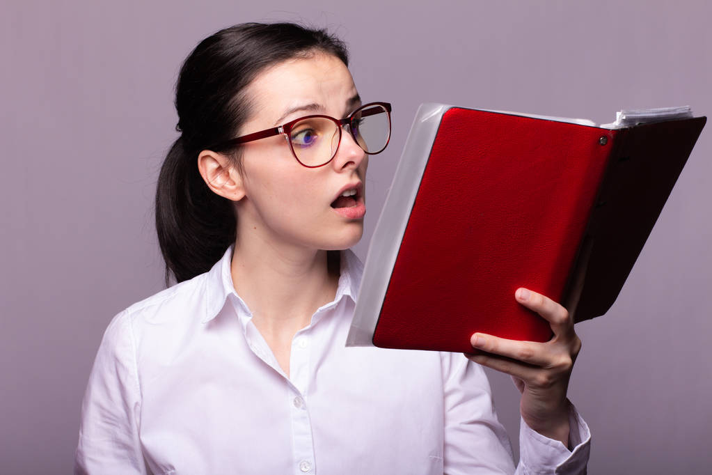 lány egy fehér inget és poharakat tart egy piros notebook a kezében - Fotó, kép