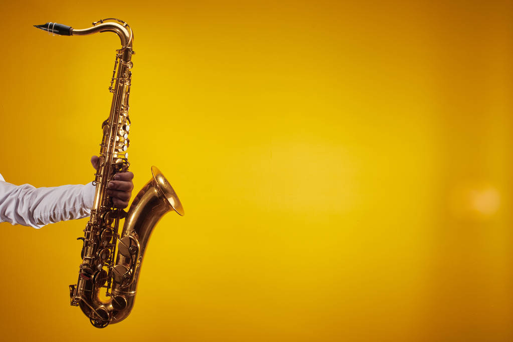 Saxofon na žlutém pozadí ve fotostudiu s volným prostorem pro kopírování - Fotografie, Obrázek