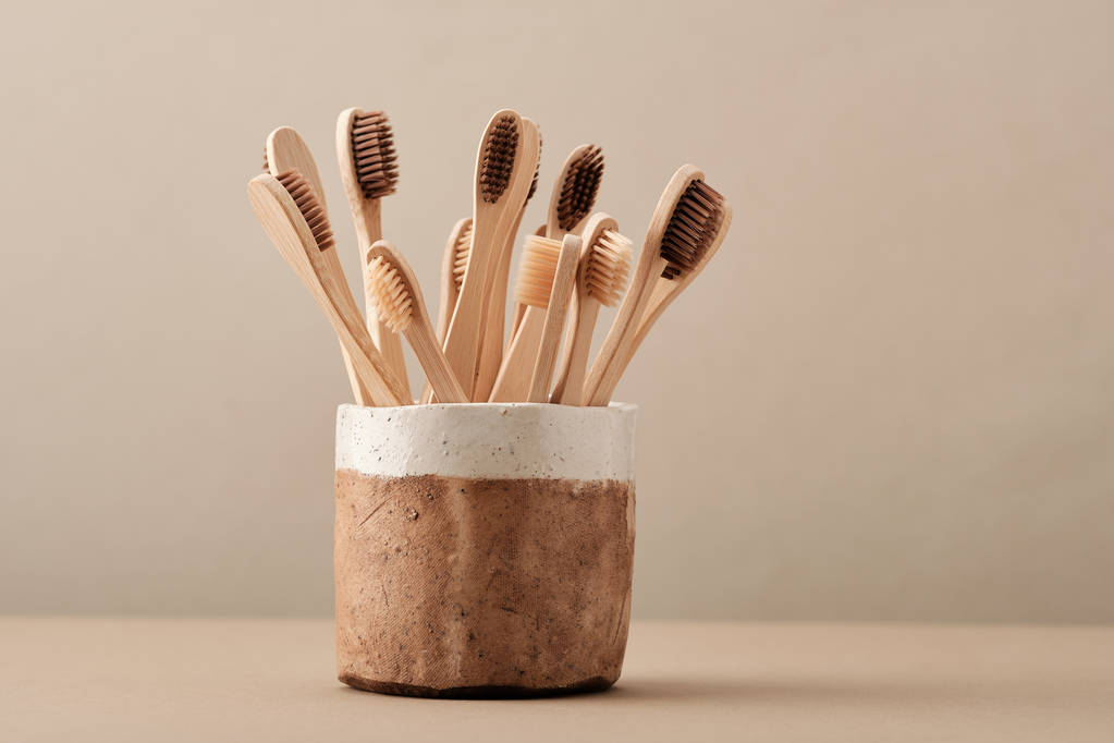 Brosse à dents Eco en bois dans une tasse en céramique marron
 - Photo, image