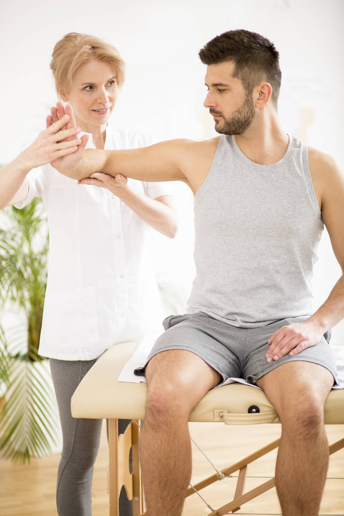 Handsome young man during physiotherapy session with professional doctor - Photo, Image