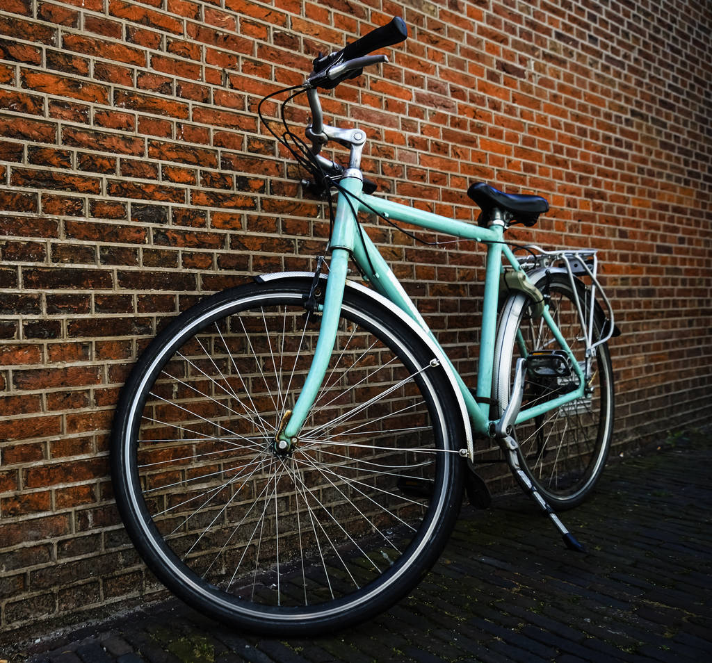 Blue vintage city bicycle without basket standing near red brick wall. - Photo, Image