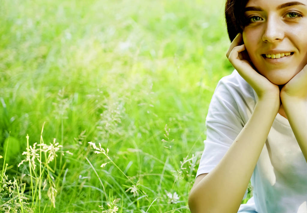 Retrato bonito de pensive jovem menina de cabelos curtos no fundo do prado grama verde borrada, close-up
.  - Foto, Imagem