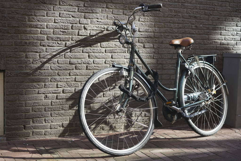 schwarzes klassisches Rennrad an graue Ziegelwand gelehnt in der Sonne mit Schatten und Platz für Text oder Kopie - Foto, Bild