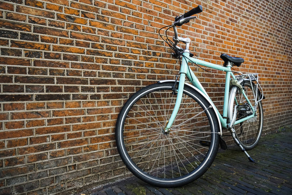 bicicleta de ciudad vintage azul sin cesta de pie cerca de la pared de ladrillo rojo
. - Foto, imagen