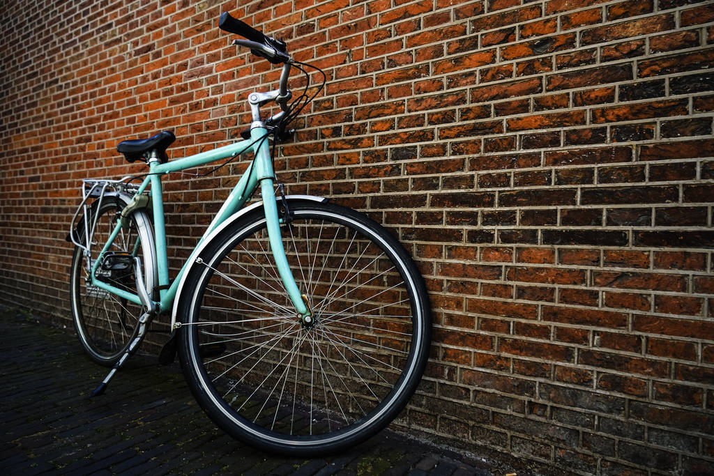 Bicicleta da cidade vintage azul sem cesta de pé perto da parede de tijolo vermelho
. - Foto, Imagem