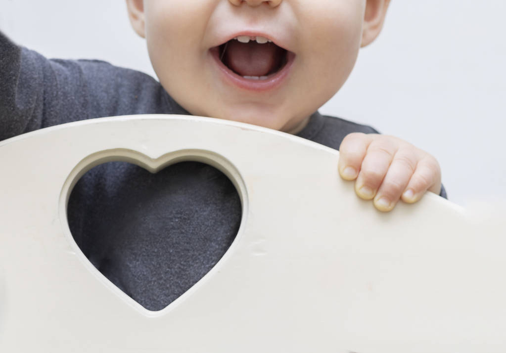 Close-up portrait of a smiling child's mouth. Focus on the heart and place for text, copy space, free space, the child is blurred, out of focus. The concept of health and love, St. Valentine - Photo, Image