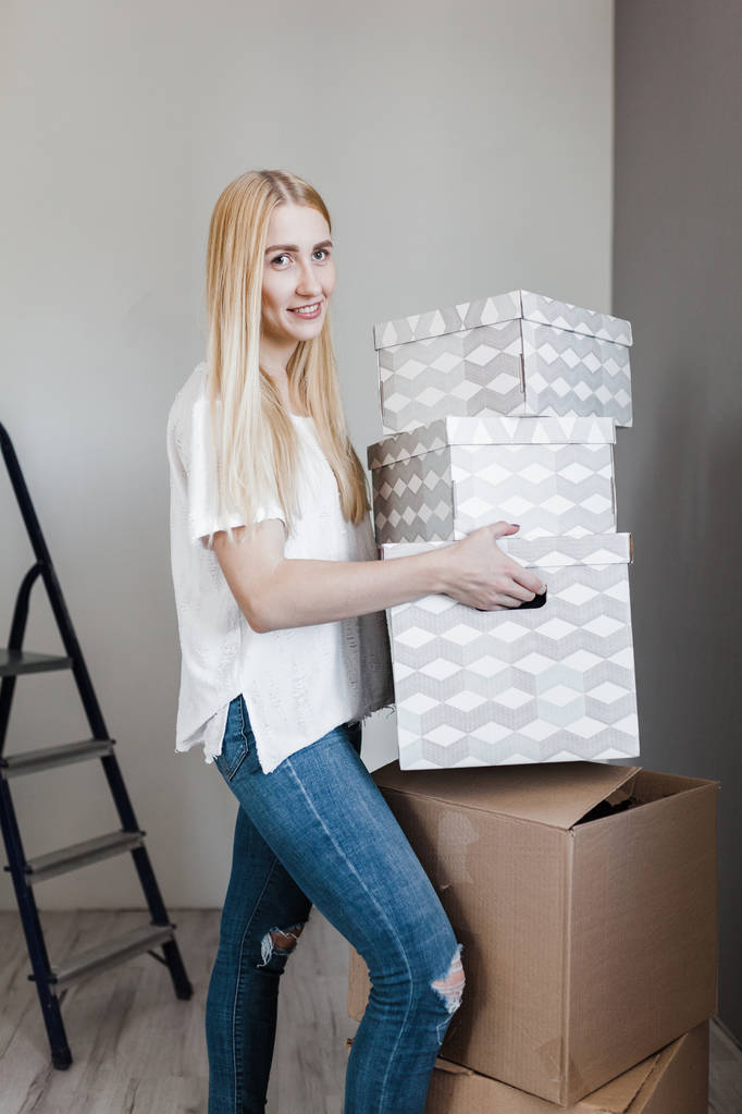ипотека, люди и концепция недвижимости - счастливая женщина с коробками, переезжающими в новый дом
 - Фото, изображение