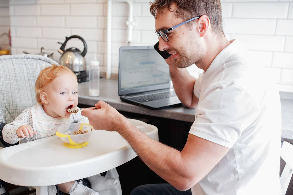 Happy young father working at home and sitting with a baby girl. - Photo, Image