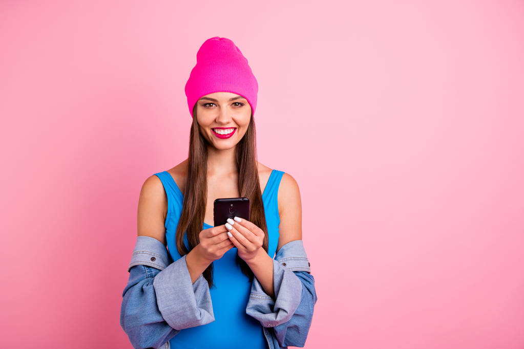 Retrato de la encantadora dama que sostiene el dispositivo sonriendo usando ropa de baño azul aislada sobre fondo rosa
 - Foto, imagen