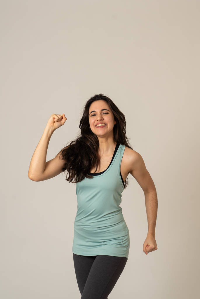 Wesoły łaciński silny Kobieta w Sportswear patrząc zdrowy i seksowny. Portret pasuje młoda kobieta ubrana w siłowni Top pozowanie szczęśliwy i zabawny w rozciąganie i trening stwarza w fitness i Pielęgnacja ciała koncepcja. - Zdjęcie, obraz