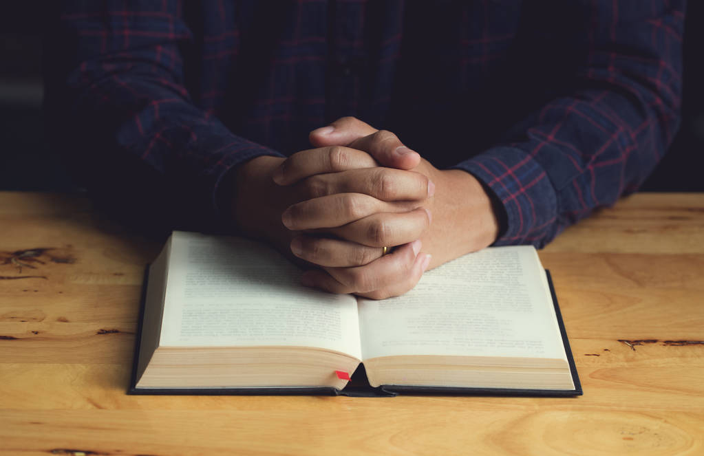 Mani di preghiera giovane uomo e la Bibbia su una tavola di legno
. - Foto, immagini
