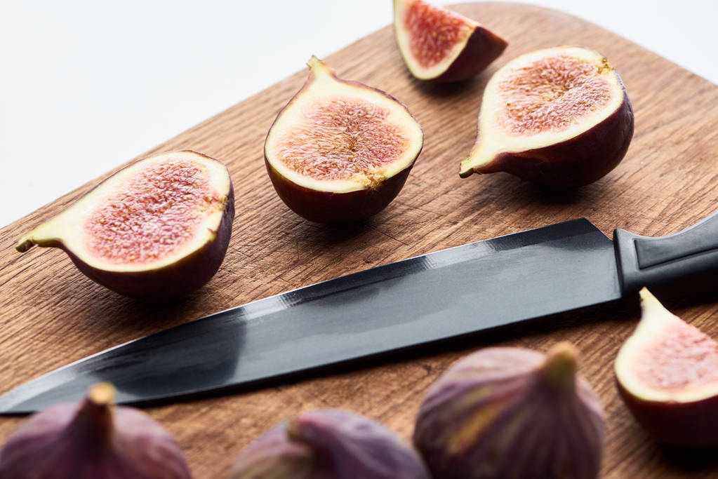 maduro entero y cortar deliciosos higos en tabla de cortar de madera con cuchillo aislado en blanco
 - Foto, Imagen