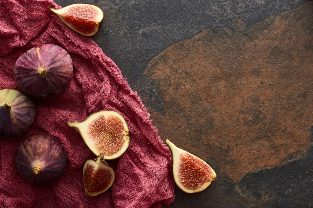 vista superior de higos maduros enteros y cortados deliciosos sobre tela roja rústica sobre fondo de piedra
 - Foto, Imagen