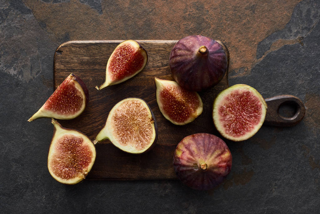 top view of ripe cut delicious figs on cutting board on stone background - Photo, Image