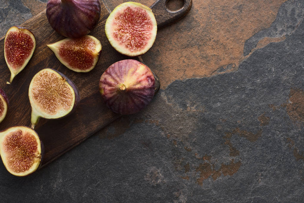 top view of fresh cut figs on wooden cutting board on stone table - Photo, Image