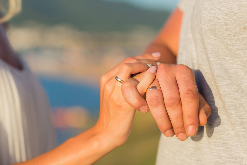 結婚指輪を持つ男女の写真。手をつないでいる若い夫婦、結婚式の日。結婚指輪を持つ新婚カップルの手 - 写真・画像