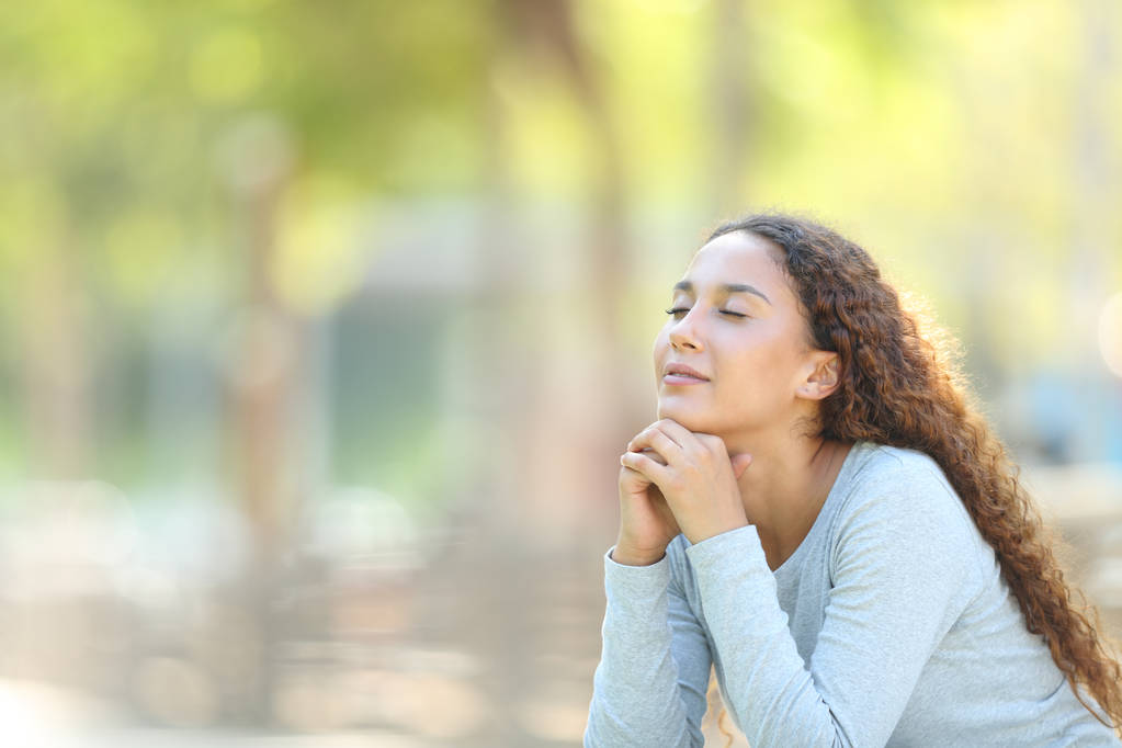 Жінка змішаної раси розслабляється роздумуючи в парку
 - Фото, зображення