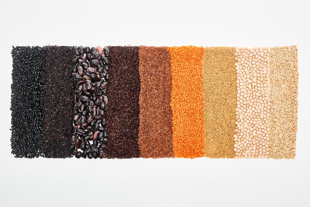 pohled na rozmanité černé fazole, rýži, quinoa, pohanku, cizrnici a červenou čočku izolovanou na bílém - Fotografie, Obrázek