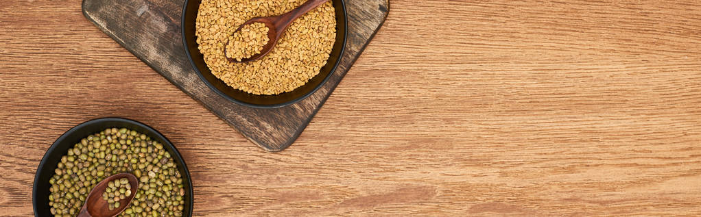 tahta kesme tahtası üzerinde kaşık ile tahıl ve maash fasulye ile siyah kase panoramik çekim - Fotoğraf, Görsel