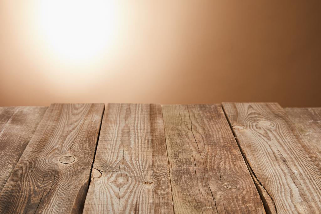 άδειο ξύλινο τραπέζι σε καφέ φόντο με φακό - Φωτογραφία, εικόνα