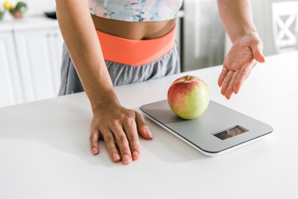 cropped view of woman gesturing near food scales and apple  - Photo, Image