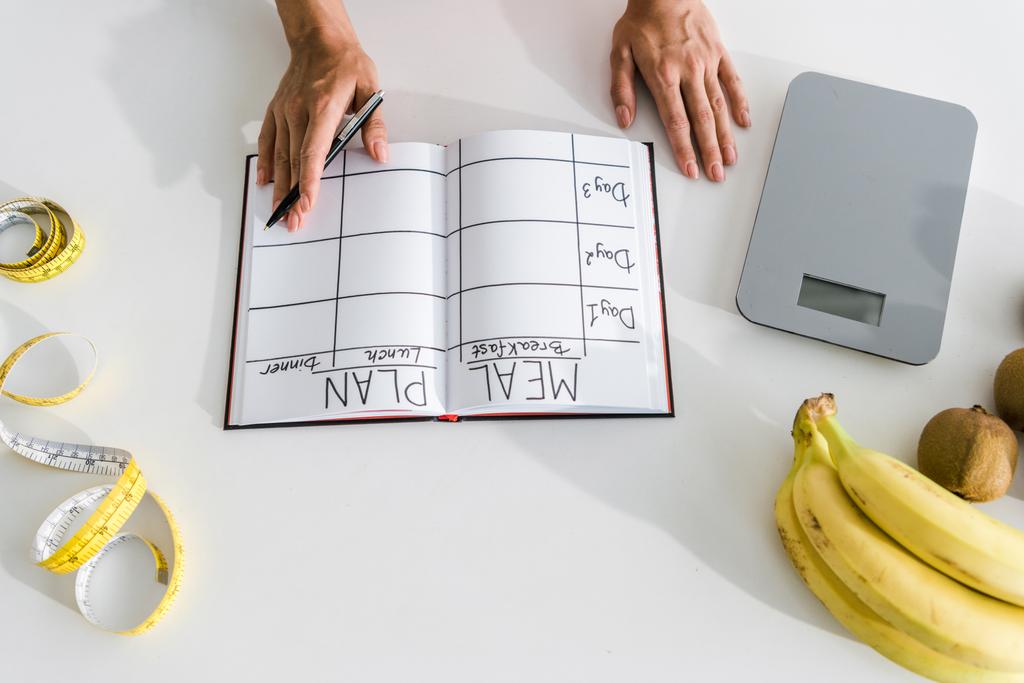 vista ritagliata di donna che tiene penna vicino notebook e frutta
  - Foto, immagini