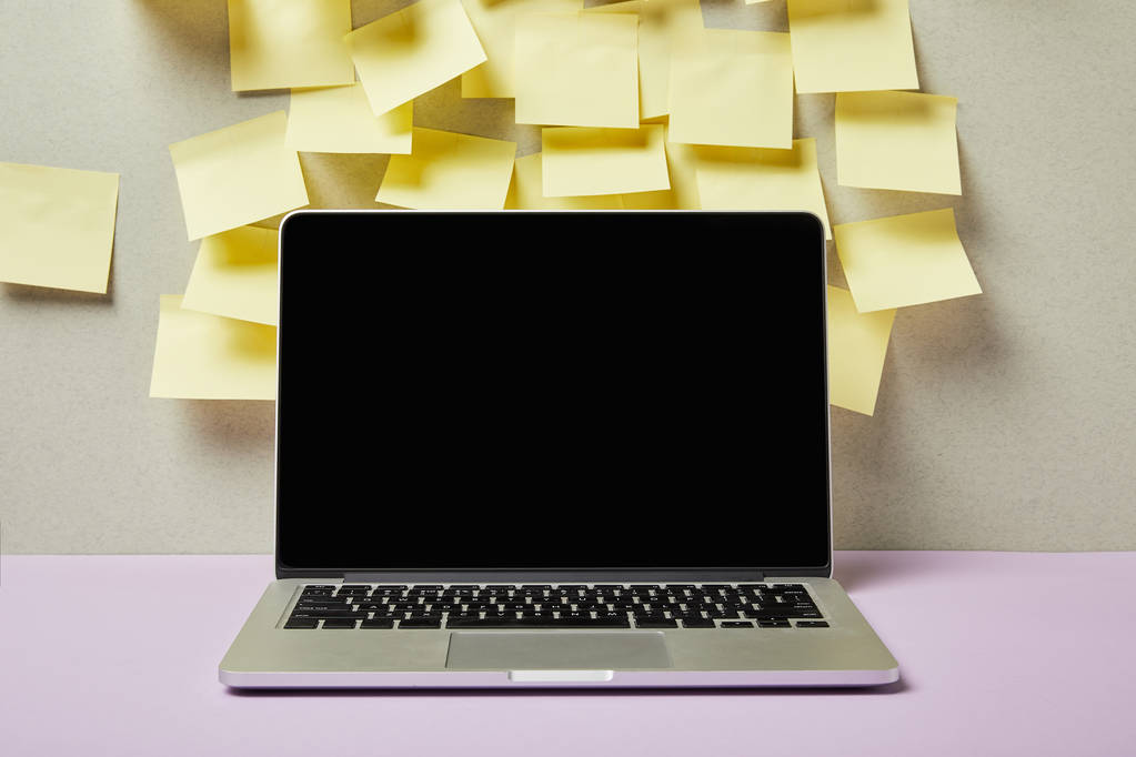 laptop com tela em branco perto de notas pegajosas amarelas em cinza e roxo
  - Foto, Imagem
