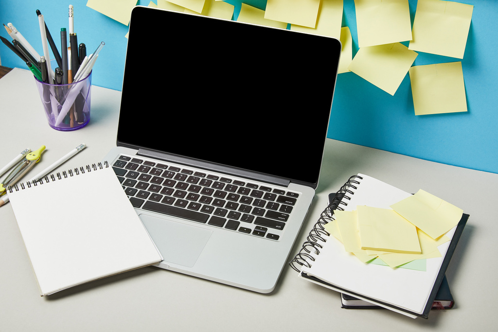 laptop con pantalla en blanco cerca de notas adhesivas papelería y cuadernos en azul y blanco
  - Foto, Imagen