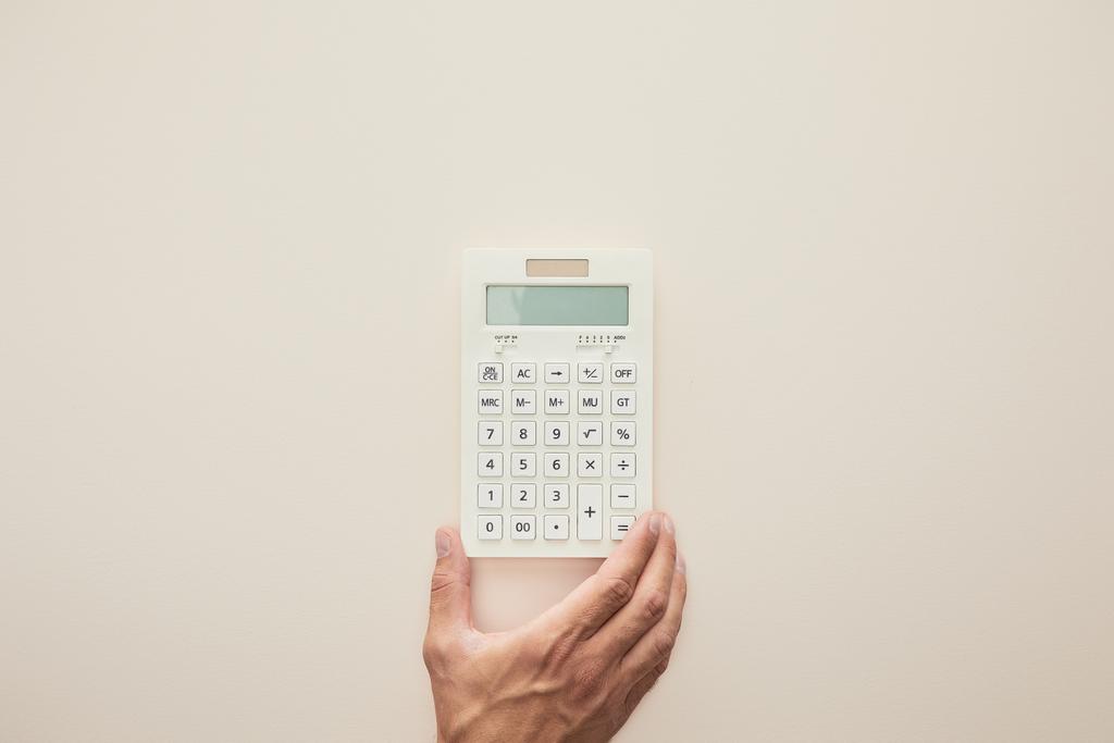 καλλιεργημένη άποψη του ανθρώπου που κρατά αριθμομηχανή απομονωμένη σε μπεζ  - Φωτογραφία, εικόνα