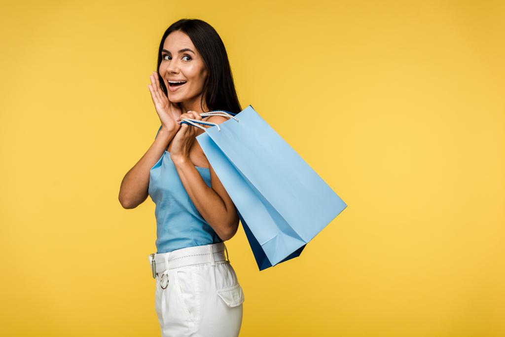excited woman holding shopping bags isolated on orange  - Photo, Image