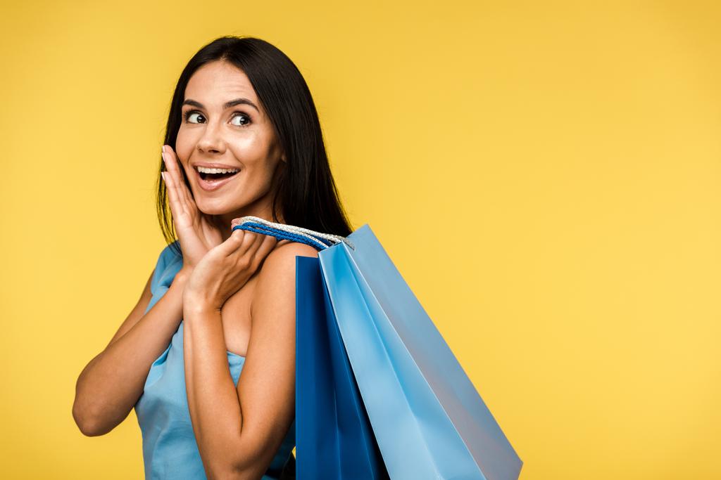 excited young woman holding shopping bags isolated on orange  - Photo, Image