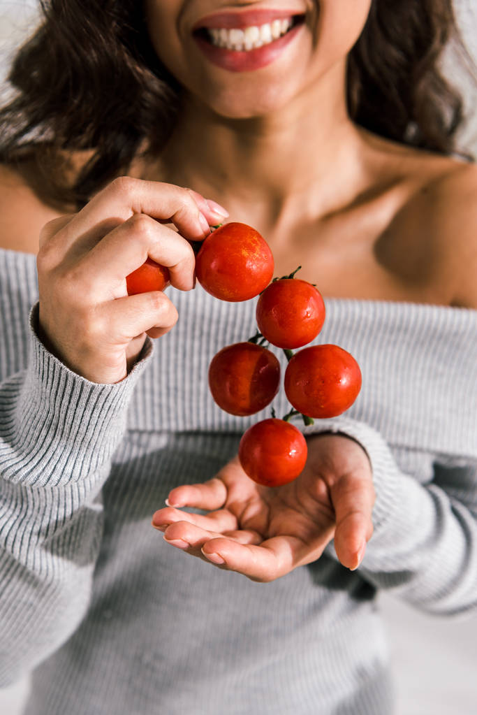 обрізаний вид щасливої жінки, що тримає червоні та свіжі вишневі помідори
  - Фото, зображення