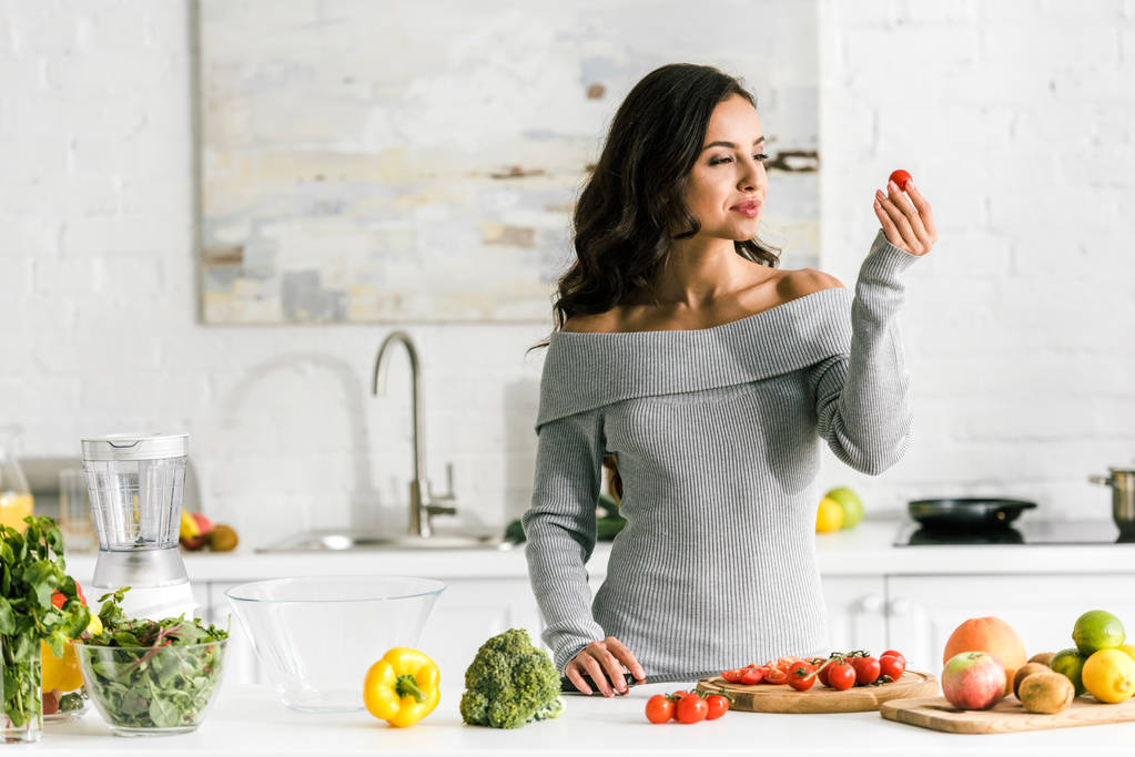 atrakcyjna kobieta trzymanie pomidorów Cherry w pobliżu warzyw  - Zdjęcie, obraz