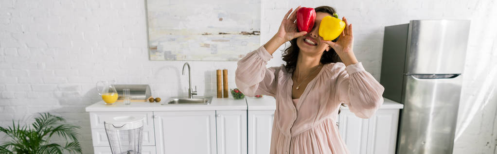 colpo panoramico di donna felice con paprica rossa e gialla in mano
  - Foto, immagini