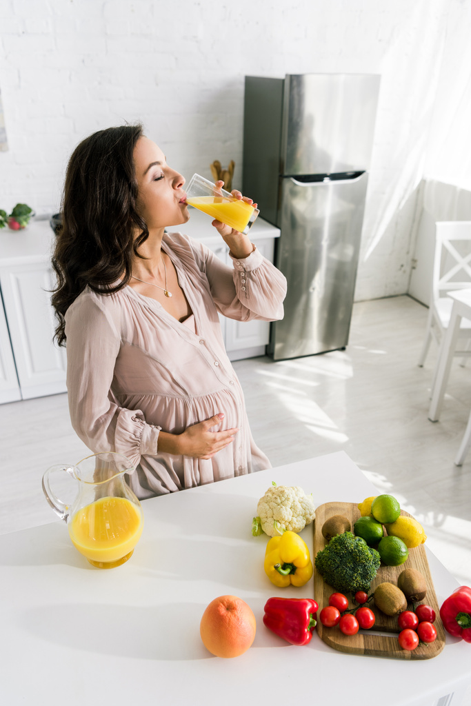 houkutteleva raskaana oleva nainen juo tuoretta appelsiinimehua
  - Valokuva, kuva