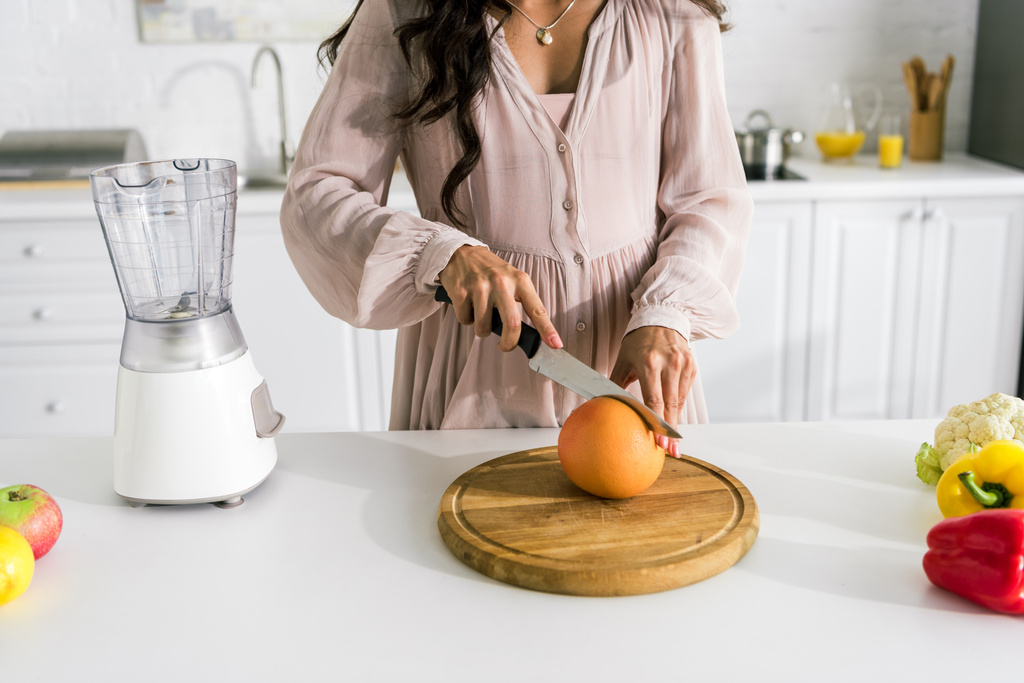 обрезанный вид беременной женщины, режущей грейпфрут
  - Фото, изображение