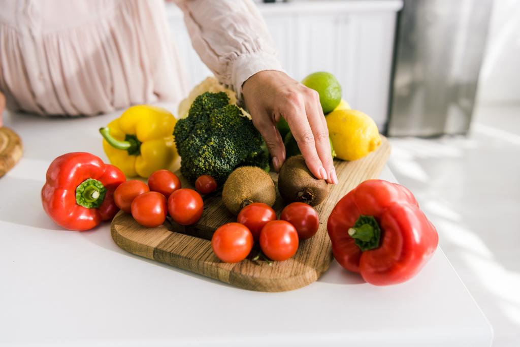 vue recadrée de la femme enceinte touchant kiwi près des légumes
  - Photo, image